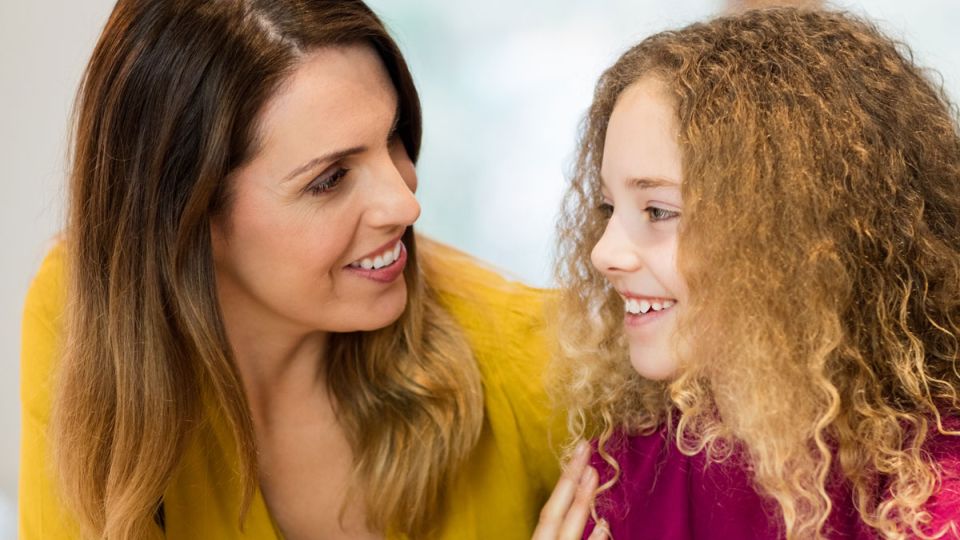 A smiling kid talking with her mother